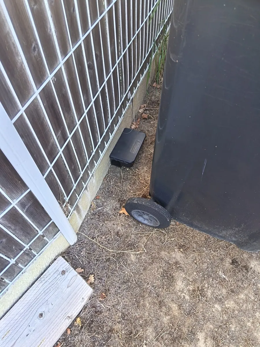 Poste d appâtage sécurisé et fixé le long d une clôture près des poubelles d une maison en Gironde